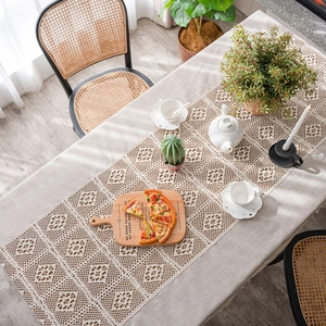 Beige boho crochet tablecloth with geometric floral hollow patterns on a wooden table