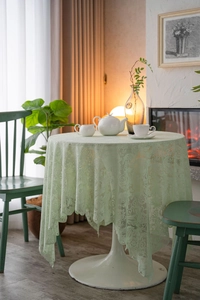 Close-up of mint green lace tablecloth with intricate floral patterns and pearl bead edges