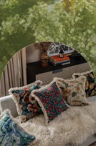 Dettaglio della federa jacquard a fiori con nappe color crema in un ambiente retrò