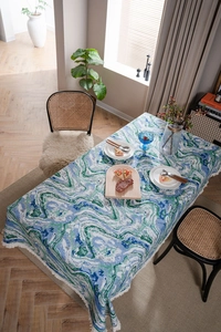 Detailed view of heavy fabric tablecloth with green marble pattern and white tassels