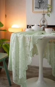 Detail of light green lace tablecloth with floral embroidery and white pearl beads