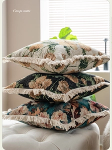 Détail de coussins à fleurs en jacquard avec franges décoratives sur un tabouret en cuir blanc