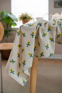 Detail of floral embroidery with yellow flowers on a beige cotton linen tablecloth