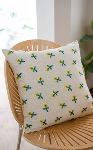 Close-up of yellow floral embroidery on beige cotton linen pillow on a wooden chair