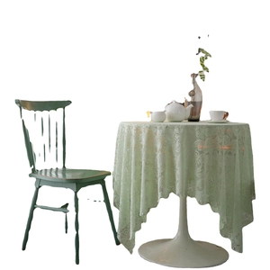 Elegant pale green lace tablecloth with floral embroidery and wavy edges on a white table