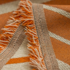 Thick geometric woven throw blanket with warm orange patterns and fringe tassels