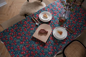 Detail of dark blue jacquard tablecloth with red apple patterns and white fringe