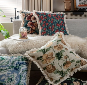 Détail de coussins en jacquard avec motifs floraux et bordures à pompons beiges