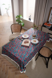 Detail of dark blue floral tablecloth with red cherry jacquard and white fringe tassels