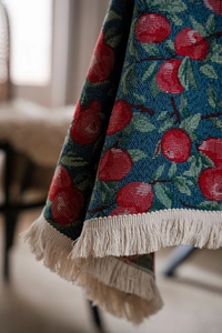 Detail of navy blue table cloth with red apple jacquard weave and cream fringe edges