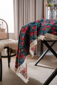 Detailed macro view of heavy blue woven tablecloth with red cherry jacquard and fringe