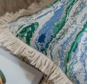 Vue détaillée d'une housse de coussin jacquard avec motif abstrait et bords à franges
