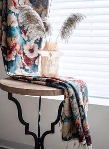 Detail of vintage floral jacquard fabric with elegant white fringe tassels on a table