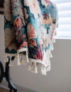 Detailed macro view of vintage floral jacquard fabric with elegant white cotton tassels