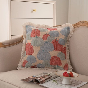 Coussin jacquard carré avec motif citrouille et franges sur un canapé beige