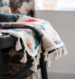 Close-up of vintage floral jacquard fabric with elegant white tassel fringe detail
