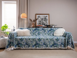 Detail of a thick jacquard sofa cover with blue marble fluid pattern and cream tassels