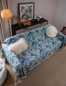 Detail of abstract marble pattern sofa throw with white fringe trim and jacquard texture