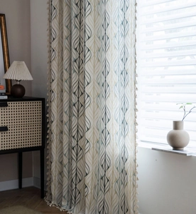 Detail of vintage cotton linen curtain with geometric leaf print and beige tassel trim