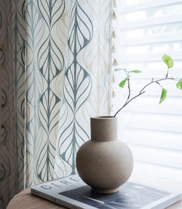 Detailed view of linen curtain with blue leaf print and decorative tassel trim