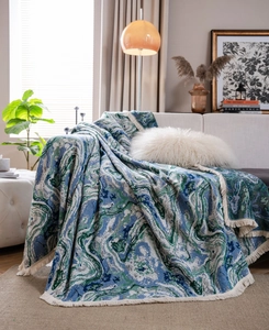 Close-up of thick jacquard sofa throw with blue marble pattern and white tassel edges