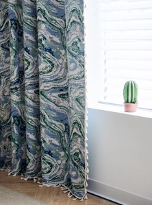 Detail of blue marble jacquard fabric curtains with elegant cream white tassel edge