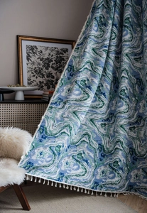 Close-up of blue and green marble jacquard textile with elegant white fringe details