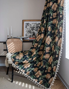 Close-up of vintage floral jacquard curtain with tassels in warm natural window sunlight