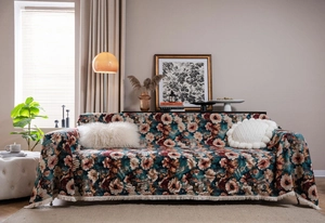 Close-up of vintage floral jacquard sofa cover with cream fringe tassels in rustic style