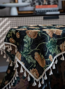 Detail view of black jacquard fabric with orange floral pattern and cream tassel trim