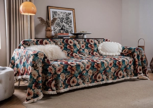 Detail of floral tapestry throw with elegant beige fringes on a vintage green sofa