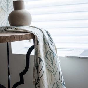 Vintage floral linen curtain with leaf print and tassel fringe on a dark wood table