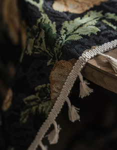 Macro detail of vintage floral jacquard fabric with elegant cream tassels and fringe