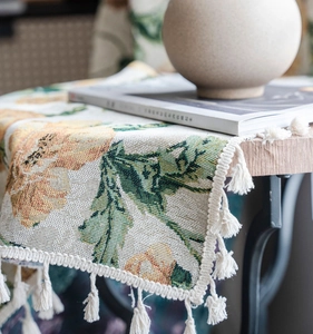 Nahaufnahme von gelbem Jacquard-Blumenmuster und weißen Baumwollquasten am Tischläufer