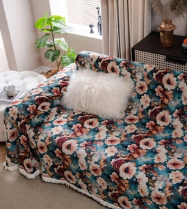Close-up of vintage floral sofa throw with navy blue fabric and white decorative tassels
