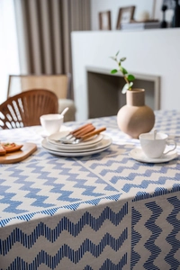 Close-up of blue and white zigzag linen tablecloth with textured weaving and ceramic decor