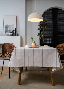 Detail of cream rectangular tablecloth with black stripes on a wooden dining table