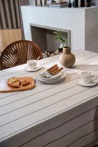 Detail of grey striped linen tablecloth draped over a dining table in a cozy home setting