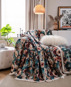 Detailed view of heavy jacquard floral fabric texture and long fringe edges of the sofa cover