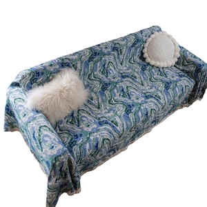 Blue and green marble pattern sofa cover with fringe edges on a modern couch