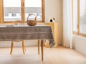 Detail of rustic brown cotton linen tablecloth with white geometric pattern and fringe
