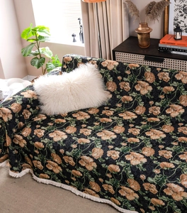 Close-up of vintage floral sofa cover with orange flowers and elegant white fringe trim
