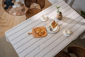Detail view of woven striped linen tablecloth with a rustic wooden dining table setting