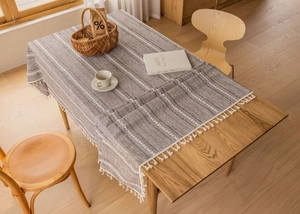 Close-up of dark brown linen tablecloth with white diamond patterns and cotton tassels