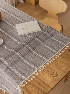 Detail of dark brown table runner with white diamond embroidery and fringe tassels