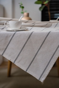 Close-up detail of beige striped cotton linen tablecloth with natural drape and texture