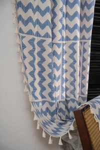 Détail de motif géométrique bleu sur rideau en lin avec de petits pompons à franges