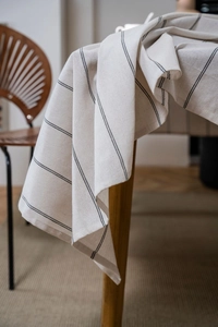 Close-up detail of minimalist cream linen tablecloth with black vertical stripe pattern