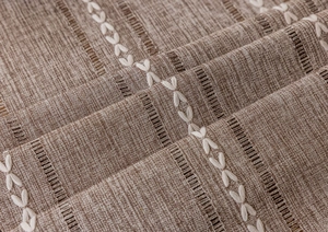 Detailed close-up of brown linen blend tablecloth with white X-embroidery and hemstitch