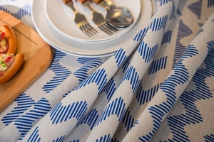 Detail view of cotton linen tablecloth with blue geometric stripes and soft drape texture